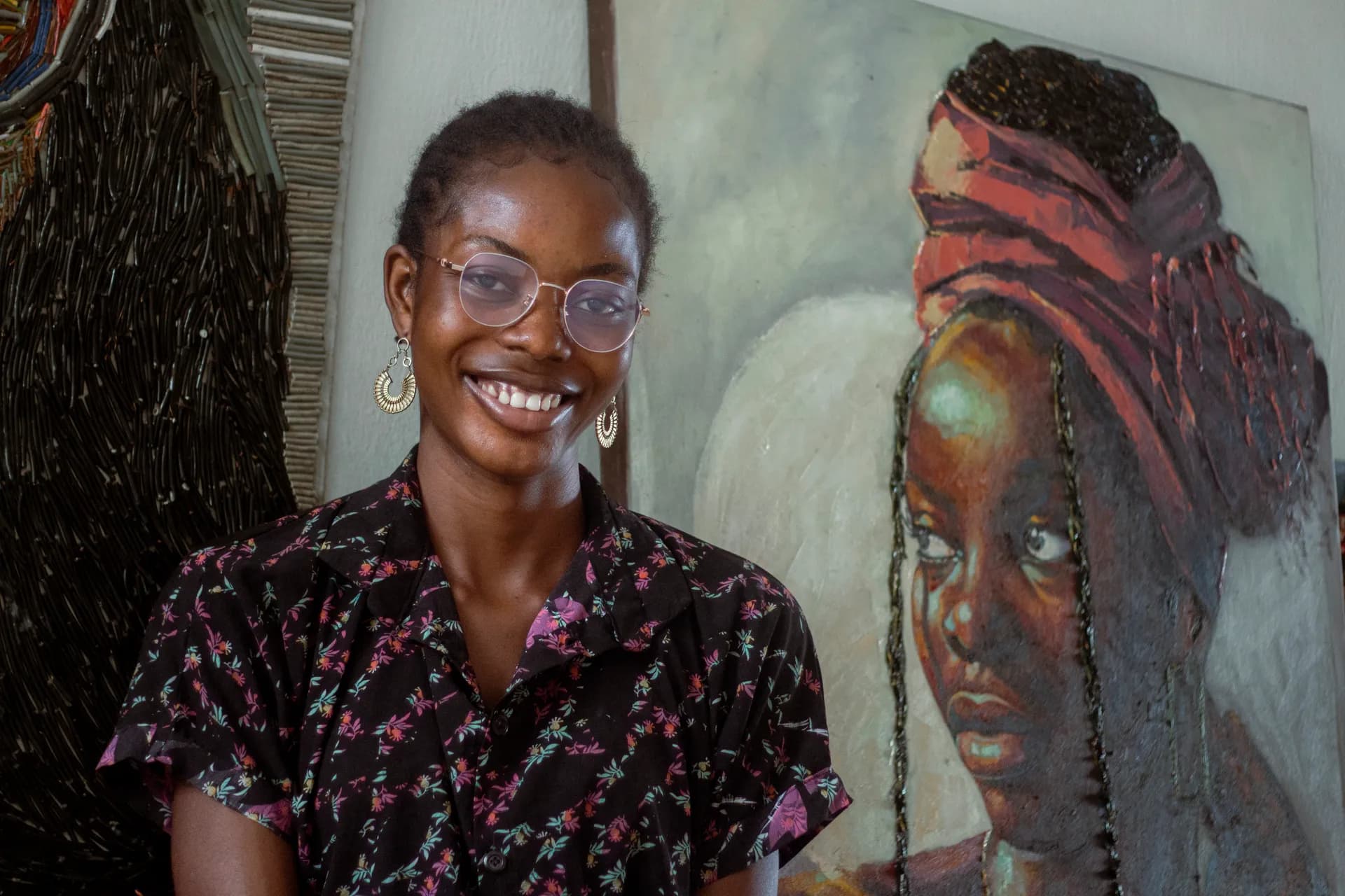 A painter standing beside two of her own portrait paintings