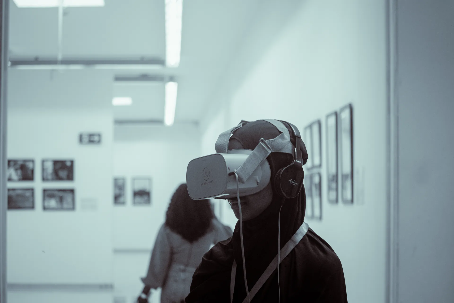 Someone wearing a VR headset in a gallery hung with photographs