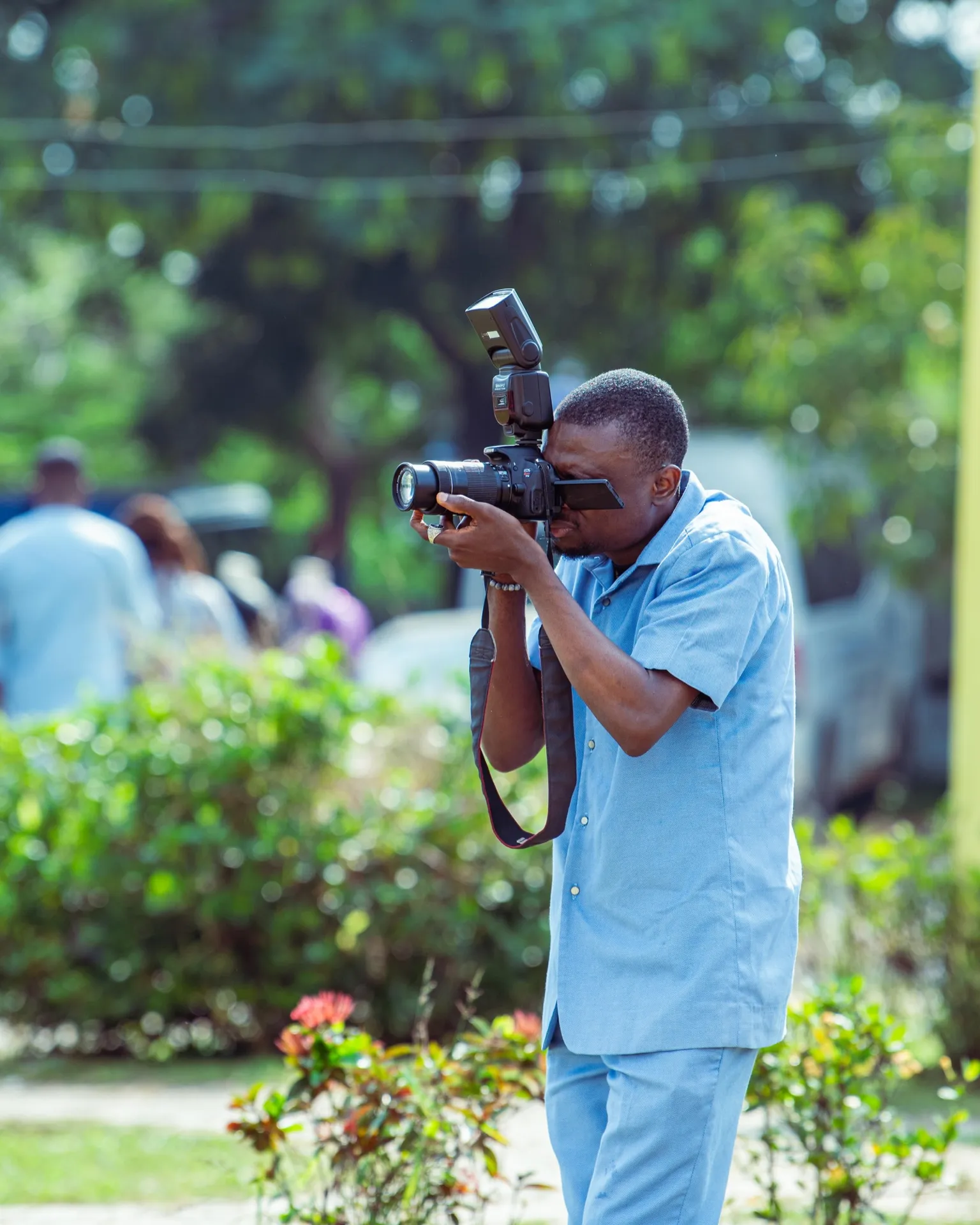 A photographer documents an outdoor session with a camera and flash.