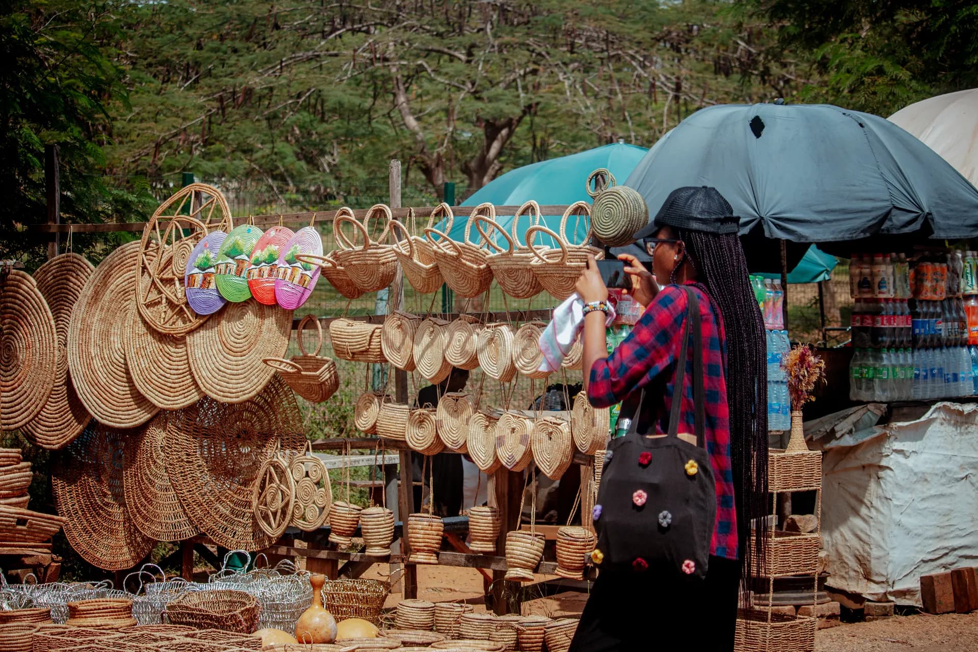 A woman photographing woven baskets on her phone at a market stall