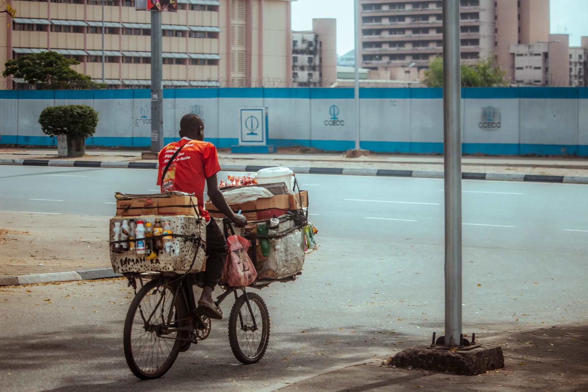 A street vendor cycling past with drinks and snacks loaded on his bicycle