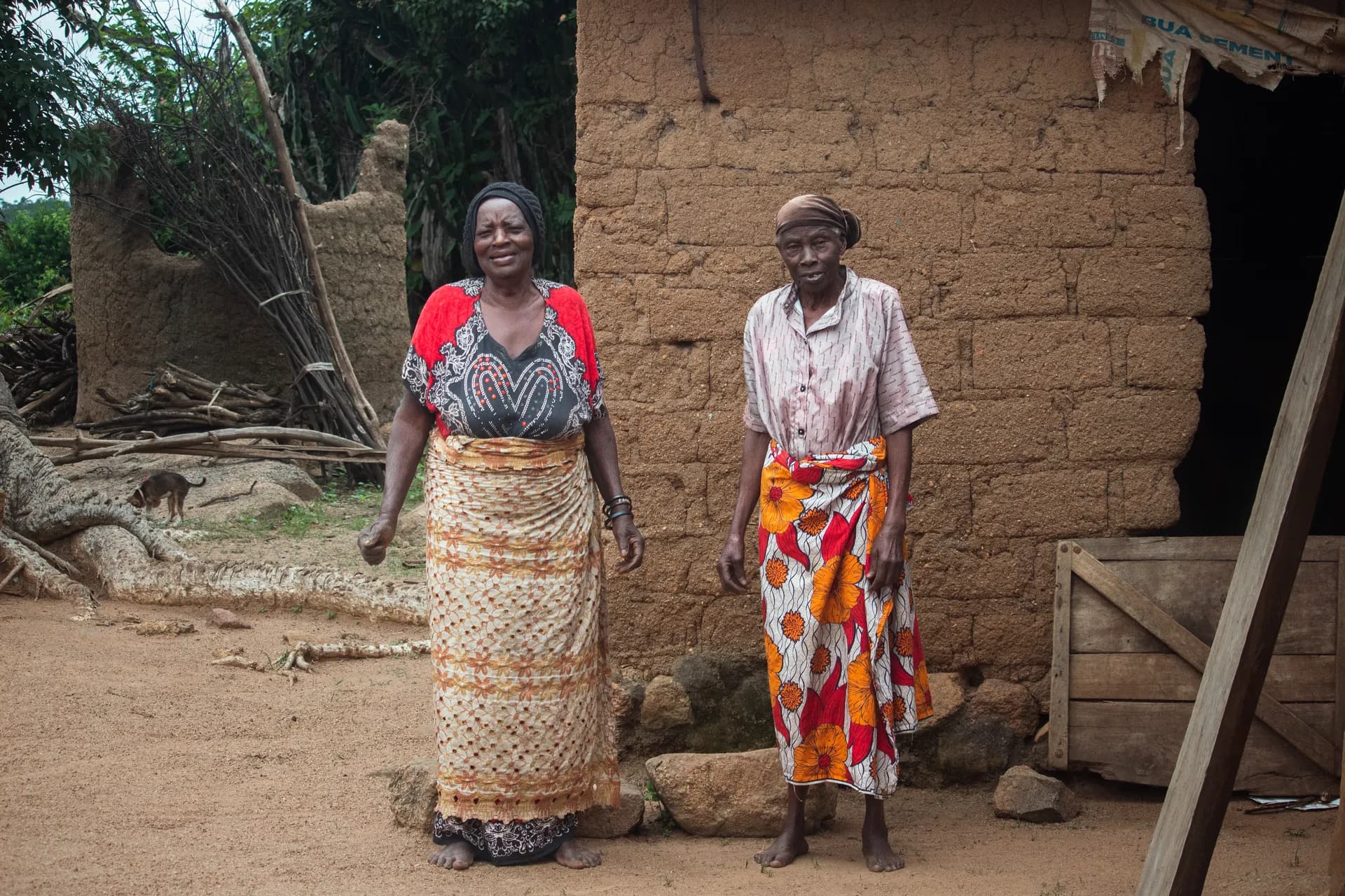 Two women standing outside a mud-brick house